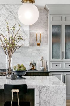 an elegant kitchen with marble counter tops and white cabinets, along with black bar stools