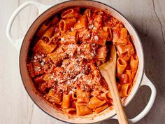 a pot filled with pasta and parmesan cheese on top of a wooden spoon