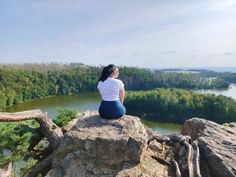 a woman sitting on top of a large rock