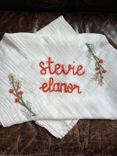 two embroidered napkins sitting on top of a leather chair