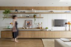 a blurry photo of a woman walking in front of a tv on a wooden shelf