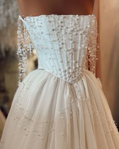 the back of a wedding dress with pearls on it's waist and neckline