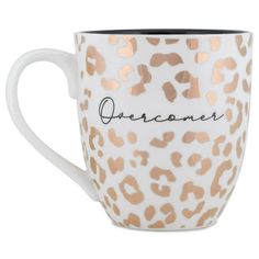 a white and gold leopard print coffee cup with the word overcome on it's side