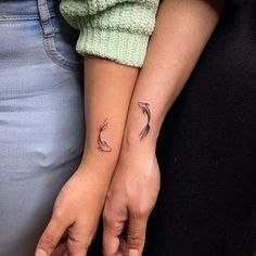 two people with matching tattoos on their arms, one holding the other's hand