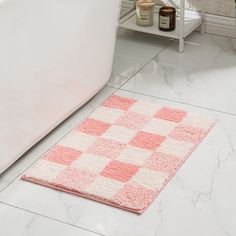 a white bath tub sitting next to a toilet in a bathroom with pink rugs on the floor