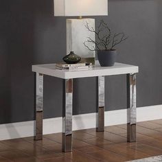 a table with a lamp on top of it in front of a gray wall and rug