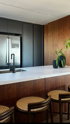 a kitchen counter with stools and a potted plant