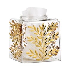 a glass tissue dispenser with gold leaves on it