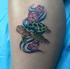 a tattoo on the leg of a woman with a turtle and flowers