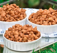 three white bowls filled with nuts sitting on top of a blue and white table cloth