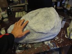 a man is making a large rock out of paper machs on a workbench