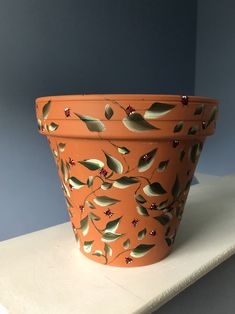 an orange flower pot sitting on top of a white shelf