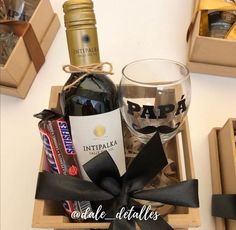 a bottle of wine and some chocolates in a wooden box with a black ribbon