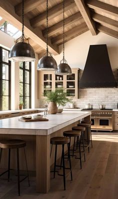 a large kitchen with wooden floors and white walls, along with an island in the middle