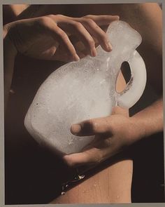 a person holding a plastic jug with ice on it's side and the bottom half of their body visible