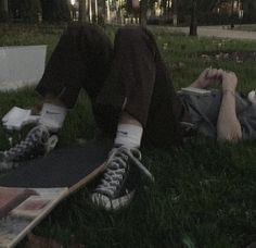 a person laying on the ground with their feet propped up next to a skateboard