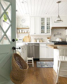 an open door leading to a kitchen with white cabinets and wood floors, along with a basket on the floor