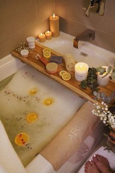 a bathtub filled with soap and candles next to a person's feet in the tub