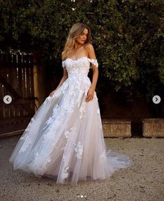 a woman in a white wedding dress standing on the ground with her hand on her hip