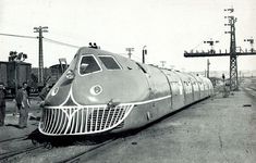 an old photo of a train on the tracks with people standing next to it and two men looking at it