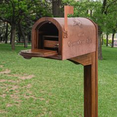 a wooden mailbox sitting on top of a lush green park