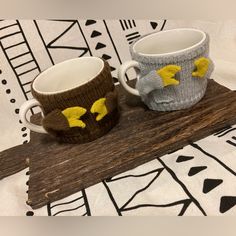 two knitted mugs sitting on top of a wooden board