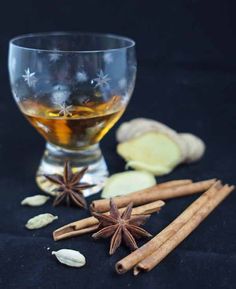 an image of spiced rum in a glass with cinnamons and cloves