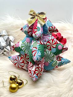 an origami christmas tree sitting on top of a white fur covered floor next to ornaments