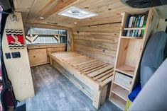 the interior of a small camper with a bed and bookshelf in it