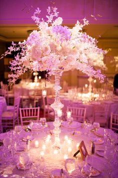 an elegant centerpiece with flowers and candles is displayed on a round table at a wedding reception