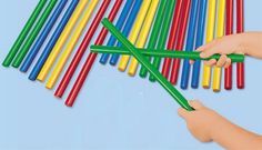 two hands are holding plastic straws with colored sticks sticking out of the top one