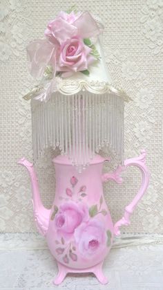 a pink tea pot with flowers on it and a birdcage in the background