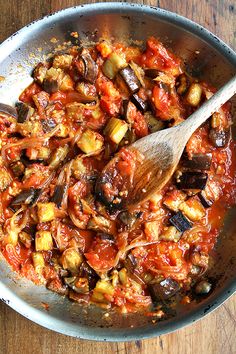 a wooden spoon in a pan filled with food