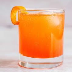 an orange drink in a glass on a table