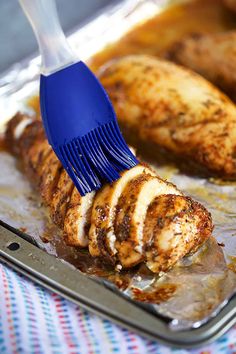 a close up of a brush cleaning chicken on a pan