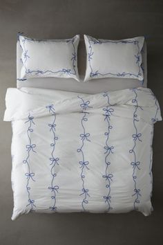 an unmade bed with two pillows on top of it and blue stringing all over the comforter