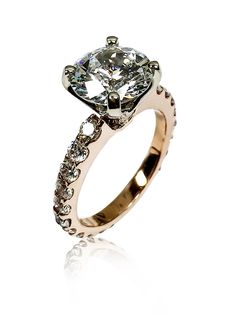 an engagement ring with diamonds on the sides and a center stone in the middle, set against a white background