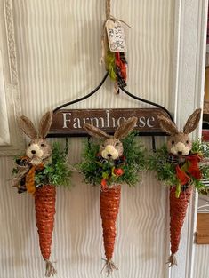 three carrots are hanging on the wall with bunny ears attached to them and flowers