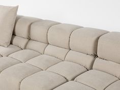 a beige couch with two pillows on it's back and one pillow that is folded over