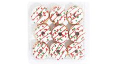 twelve decorated christmas sugar cookies in a plastic container on a white background with red and green sprinkles