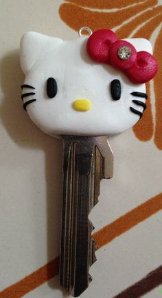 a hello kitty keychain with a red bow on it's head hanging from a wall