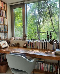 a desk with many books on it in front of a large window filled with lots of books