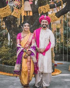 two people standing next to each other in front of a tree with decorations on it