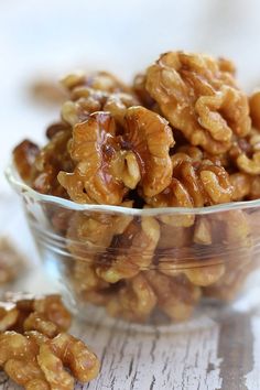 a glass bowl filled with walnuts on top of a wooden table