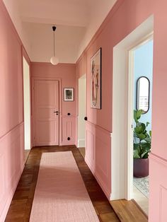 a hallway with pink walls and wooden floors