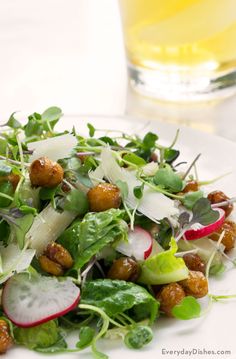 a salad with radishes, lettuce and nuts on a white plate