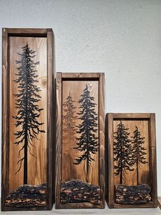 three wooden frames with trees on them sitting on top of a table next to each other