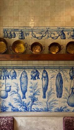 blue and white tiles on the wall in a kitchen with pots and pans above them