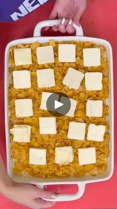 a person holding a large white container filled with cheese and crackers on top of it