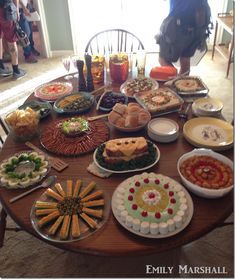 a wooden table topped with lots of plates filled with different types of food and desserts